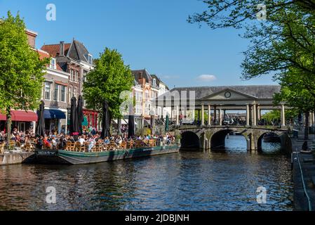 Leiden, Niederlande - 6. Mai 2022: Bootsterrasse voller Leute, die die Sonne, Essen und Getränke genießen. Das Café im Freien ist eine wichtige Freizeitbeschäftigung Stockfoto