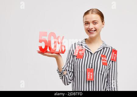 Porträt einer lächelnden Verkaufsmanagerin in einer gestreiften Bluse, die vor weißem Hintergrund steht und das Sale-Tablet zeigt Stockfoto