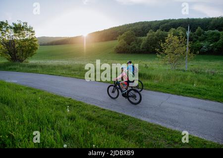 Aktives Seniorenpaar, das auf dem Trail im Sommerpark Elektrofahrräder fährt, gesundes Lifestyle-Konzept. Stockfoto