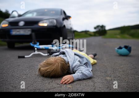 Kleiner Junge fiel vom Fahrrad und lag nach einem Autounfall noch auf der Straße. Stockfoto