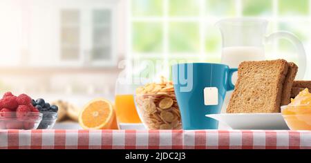 Gesundes Frühstück zu Hause mit köstlichem frischem Obst, Brot, Müsli und gesunden Getränken Stockfoto