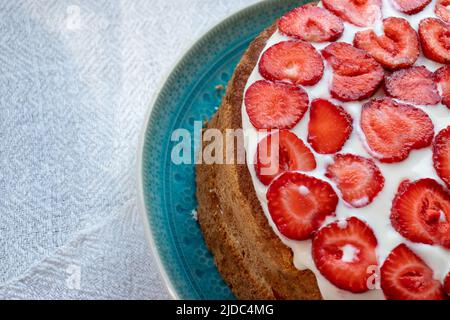Kuchen mit Erdbeeren und Rahm auf blauem Teller. Sommer Erdbeerschicht Kuchen auf weißem Hintergrund. Stockfoto