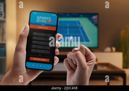 Live-in-Play-Wetten-App auf dem Smartphone-Display, eine Frau zu Hause wetten und gewinnen, POV-Shot Stockfoto