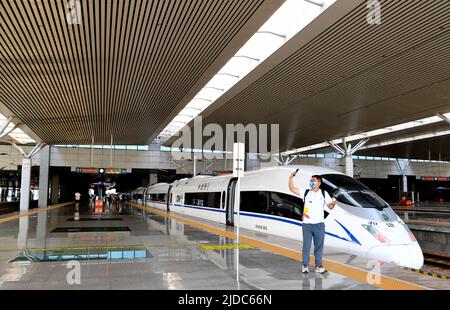 (220620) -- ZHENGZHOU, 20. Juni 2022 (Xinhua) -- Ein Passagier posiert für ein Selfie-Foto vor dem Zug G3401 im Ostbahnhof Zhengzhou in Zhengzhou, der zentralchinesischen Provinz Henan, 20. Juni 2022. Mit einer Gesamtlänge von 1.068 km nahm die Hochgeschwindigkeitsbahn Zhengzhou-Chongqing am Montag den vollen Betrieb auf. Durch die Linie kann die Fahrzeit von Chongqing nach Zhengzhou von etwa 8 Stunden auf 4 Stunden und 23 Minuten bei Höchstgeschwindigkeit verkürzt werden, während die kürzeste Zeit von Chongqing nach Peking von mehr als 20 Stunden auf weniger als 7 Stunden verkürzt wird. (Xinhua/Hao Yuan) Stockfoto