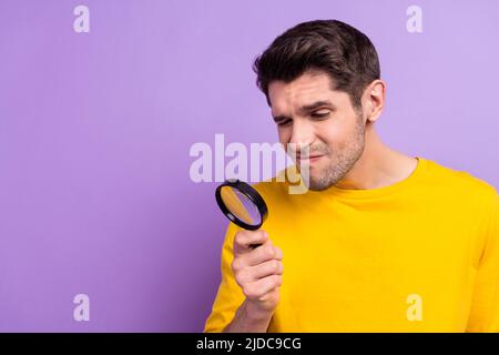 Foto von nachdenklich gesinnten lustigen Mann verwenden Lupe versuchen, etwas isoliert auf lila Hintergrund zu finden Stockfoto