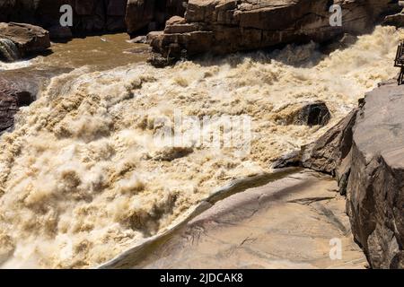 Braunes Hochwasser bei Augrabies fällt in den Oranje-Fluss in Südafrika. Stockfoto