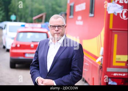 Treuenbrietzen, Deutschland. 20.. Juni 2022. Der Innenminister des Landes Brandenburg, Michael Stübgen (CDU), steht vor Feuerwehrautos im Staging-Bereich beim Waldbrand Treuenbrietzen. Starker Regen half den Feuerwehrleuten, Brände in der Nähe von Beelitz und in der Nähe von Treuenbrietzen, südwestlich von Berlin, zu löschen. Zwei große Waldflächen waren am Wochenende im Stadtteil Potsdam-Mittelmark etwa 20 Kilometer voneinander entfernt verbrannt. Quelle: Annette Riedl/dpa/Alamy Live News Stockfoto