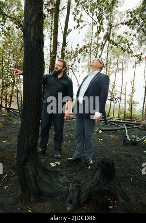 Treuenbrietzen, Deutschland. 20.. Juni 2022. Im verbrannten Wald in Treuenbrietzen steht der Innenminister des Landes Brandenburg, Michael Stübgen (CDU), neben dem Feuerwehrchef Kevin Grigorian (l.). In der Zwischenzeit wurden die Brände vollständig gelöscht. Starker Regen half den Feuerwehrleuten, Brände in der Nähe von Beelitz und in der Nähe von Treuenbrietzen, südwestlich von Berlin, zu löschen. Zwei große Waldflächen waren am Wochenende im Stadtteil Potsdam-Mittelmark etwa 20 Kilometer voneinander entfernt verbrannt. Quelle: Annette Riedl/dpa/Alamy Live News Stockfoto