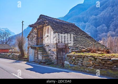 Das kleine verlassene Steinhaus mit steinernen Dach und kleiner Kapelle der Jungfrau Maria an der Fassadenwand, Mora di Fuori, Valle Verzasca, Schweiz Stockfoto