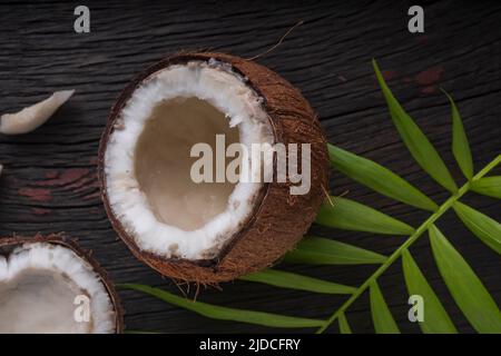 Gehackte Kokosnuss auf einem hölzernen Hintergrund, Draufsicht. Kokosmilch und Kokosflocken sind tropische Lebensmittel Stockfoto