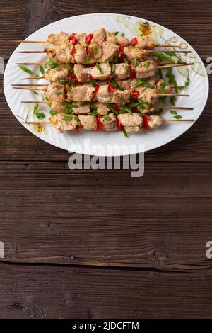 Fleischkebabs auf einer großen Platte mit Saucen und Kräutern, Holzhintergrund mit Kopierraum Stockfoto
