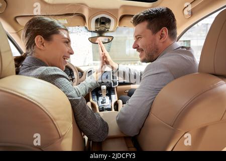 Fröhlicher Mann und Frau tun hohe fünf Geste im Auto Stockfoto