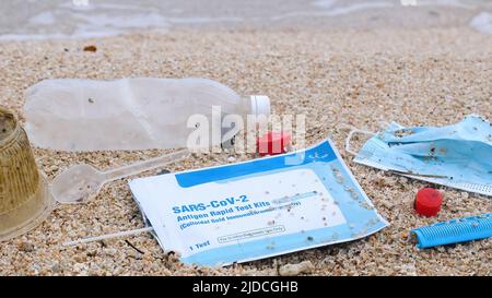 Plastikmüll zur Meeresverschmutzung - Plastikflasche, Gesichtsmaske, Selbsttest für COVID-19 am Strand. Konzept der Meeresverschmutzung. Abfall während COVID-19. Stockfoto