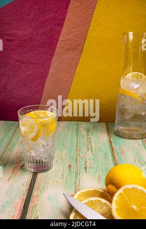 Glas und Karaffe mit Eiswürfeln, ausgewählte Fizz mit Zitronenscheiben Stockfoto