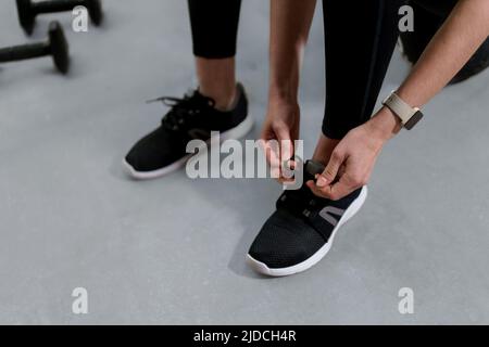 Nahaufnahme von Frauenhänden, die Schnürsenkel auf Fashion Sneakers binden Stockfoto