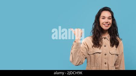 Porträt von froh junge kaukasische Frau Brünette Student in beiläufiger Zeigen Finger zu leeren Raum Stockfoto