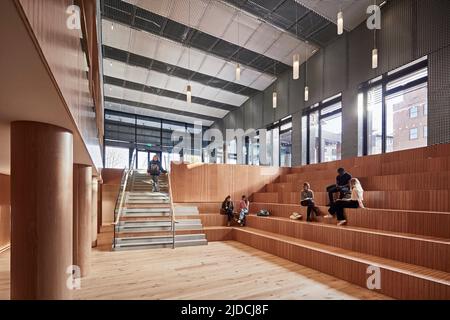 Die Studierenden plaudern und entspannen im informellen Hörsaal des Sozialen Raums. Das Hauptatrium ist mit Holzvertäfelung und einer Decke aus Metallgeflecht verkleidet Stockfoto