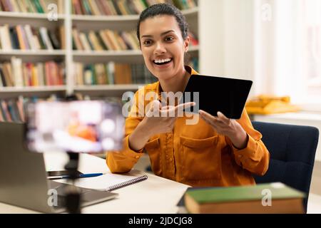 Glückliche Lehrerin, die eine Videokonferenz mit Schülern macht, die ein Tablet mit leerem Bildschirm für ein Mockup zeigen Stockfoto