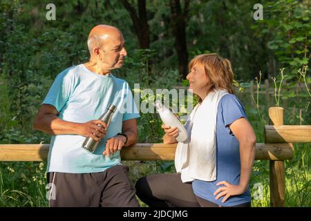 Der tägliche Lebensstil eines reifen Paares, das nach einem gemeinsamen Yoga-Klatschspass im Park steht und gemeinsam eine gute Zeit verbringt Stockfoto