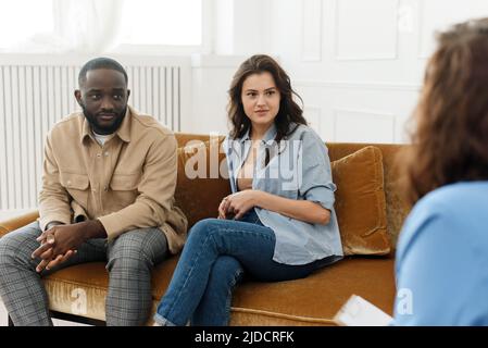 Eheberatung. Ehepartner sprechen nach einem Streit mit einem Familienpsychologen während eines Treffens, sitzen im Büro und sprechen über Ehe und Stockfoto