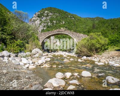 Die abgelegene Hatsios-Brücke, die sich anmutig über den Vikakis-Fluss spannt, bevor sie in die Vikakis-Schlucht - Zagori-Region des Pindus-Gebirges Griechenland einmündet Stockfoto