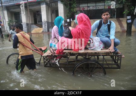 Sylhet, Bangladesch. 20.. Juni 2022. Menschen, die in Rikschas bei Überschwemmungen unterwegs sind. Die schlimmsten Überschwemmungen seit fast 20 Jahren haben Teile Bangladeschs verwüstet, Dutzende von Menschen getötet und Millionen gestrandet. Stockfoto