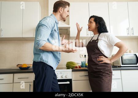Irrter Kerl, der sich mit seiner weiblichen Ehepartnerin streitete Stockfoto