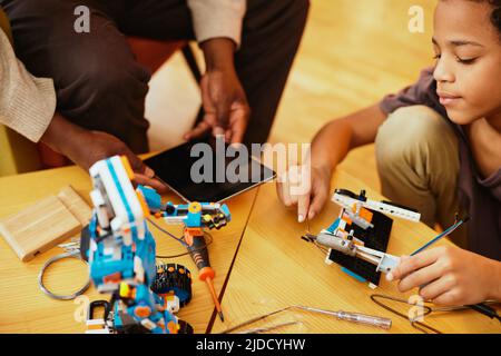 Ein Großvater und ein Enkel bauen zu Hause einen Roboter zusammen. Ausbildung in Robotik und Elektronik. Stockfoto