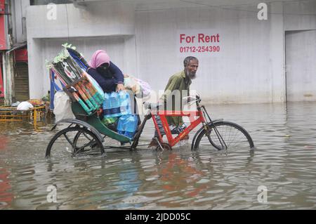 Sylhet, Bangladesch. 20.. Juni 2022. Menschen, die in Rikschas bei Überschwemmungen unterwegs sind. Die schlimmsten Überschwemmungen seit fast 20 Jahren haben Teile Bangladeschs verwüstet, Dutzende von Menschen getötet und Millionen gestrandet. Stockfoto