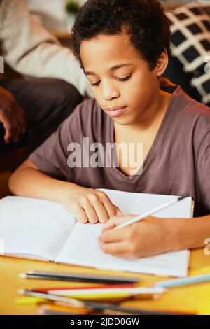 Intelligenter afrikanischer Junge, der seine mathematischen Hausaufgaben mit ein wenig Hilfe seines Opa macht. Nachhilfe und Bildung Stockfoto