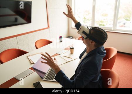 Der Mann berührt die unsichtbare Barriere, während er ein VR-Headset trägt Stockfoto