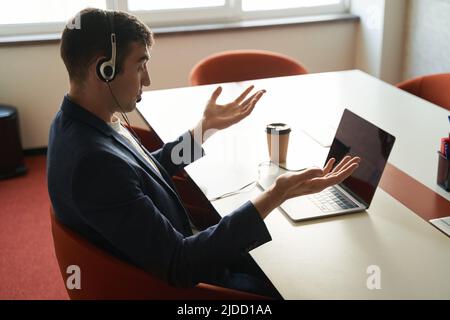 Der Mann überraschte etwas, während er Online-Geschäfte auf einem Laptop machte Stockfoto