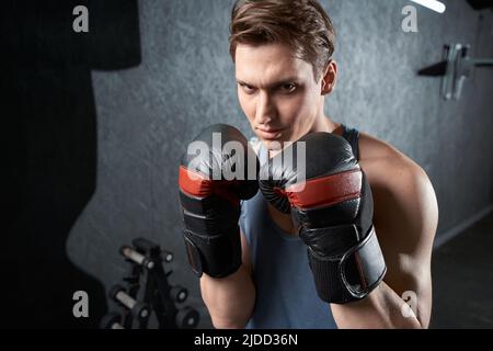 Junger entschlossener Boxer, der in hockender Haltung steht Stockfoto