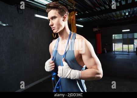 Ernsthafter junger Athlet, der im Fitnessstudio steht Stockfoto