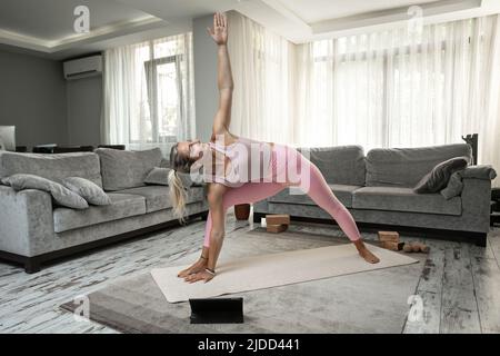 Frau praktiziert Yoga Posen Stretching vor dem Tablet-Laptop zu Hause Blogger Lehrer Yoga online Stockfoto