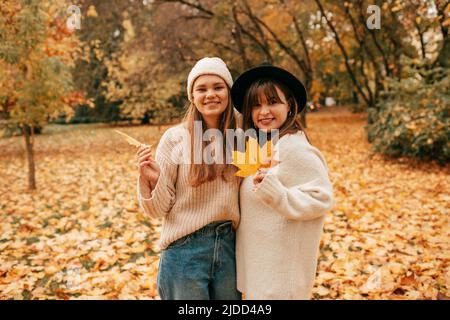 Schöner Herbsttag unter fliegenden Bäumen im Stadtpark für zwei glückliche attraktive Freundinnen, die mit hellem Laub in ihren Händen posieren.gute Laune. Wochenende Stockfoto