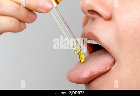 Zungenöl Pipette. Pflanzliche alternative Medizin und Nahrungsergänzungsmittel Frau, die CBD Hanföl Tropfen in den Mund von Tropf. Ergänzung und Alternat Stockfoto