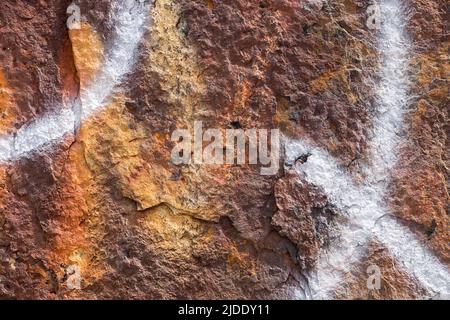 Abstrakte Muster und Graffiti-Zeichnungen über einer rostigen Boje-Oberfläche Stockfoto