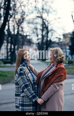 Eine Großmutter, die sich mit ihrer Enkelin verklebte, während sie stand und die Hände hielt. Stockfoto