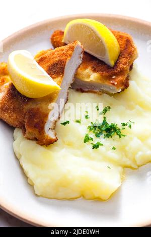 Hühnchen-Schnitzel mit Kartoffelpüree und Zitrone Stockfoto