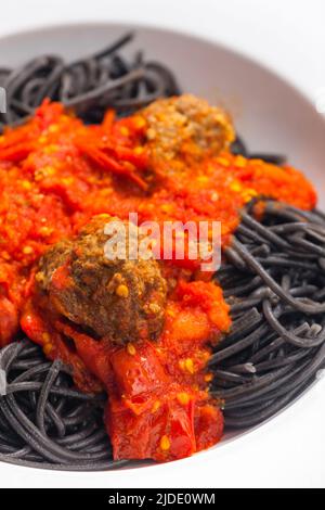 Schwarze Spaghetti mit Tomatensauce und Fleischbällchen Stockfoto