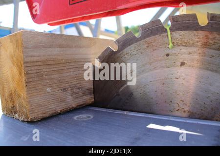 Ein Stück Holz liegt am Sägeblatt einer Kreissäge an Stockfoto