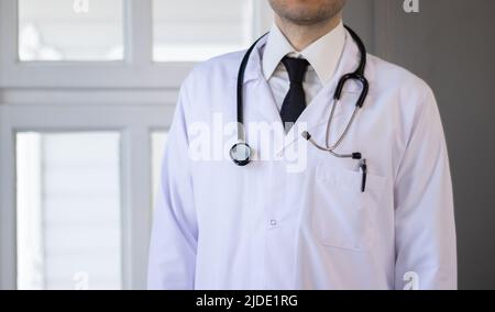 Männlicher Arzt mit Stethoskop und weißem Mantel Stockfoto