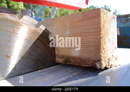 Ein Stück Holz liegt am Sägeblatt einer Kreissäge an Stockfoto