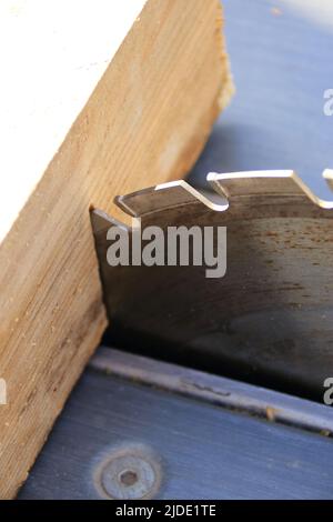 Ein Stück Holz liegt am Sägeblatt einer Kreissäge an Stockfoto