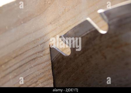 Ein Stück Holz liegt am Sägeblatt einer Kreissäge an Stockfoto