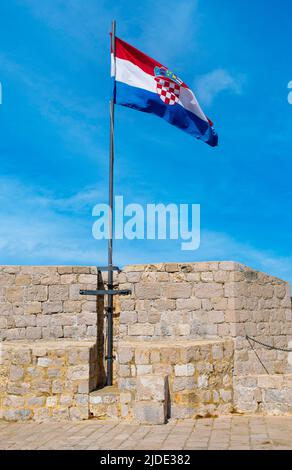 Die kroatische Flagge fliegt an einem frühen Sommermorgen in Dubrovnik hoch über der Stadtmauer der Altstadt Stockfoto