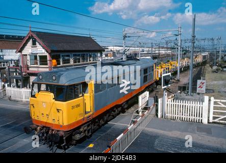 Eine Diesellokomotive der Baureihe 31 der Baureihe 31186 mit dem Oberleitungswartungszug passiert am 8.. Juli 1990 den Signalkasten und den Bahnübergang am Dagenham Dock. Stockfoto