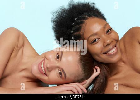 Junge schöne kaukasische und afrikanische Frauen posieren übereinander liegend, von Angesicht zu Angesicht. Lebensstil verschiedener Nationalitäten, Menschen Konzept Stockfoto