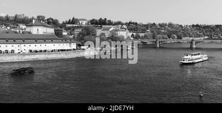 Touristenboot fährt auf der Moldau. Prager Stadtbild an einem Sommertag. Tschechische Republik. Panorama-Schwarzweißfoto Stockfoto